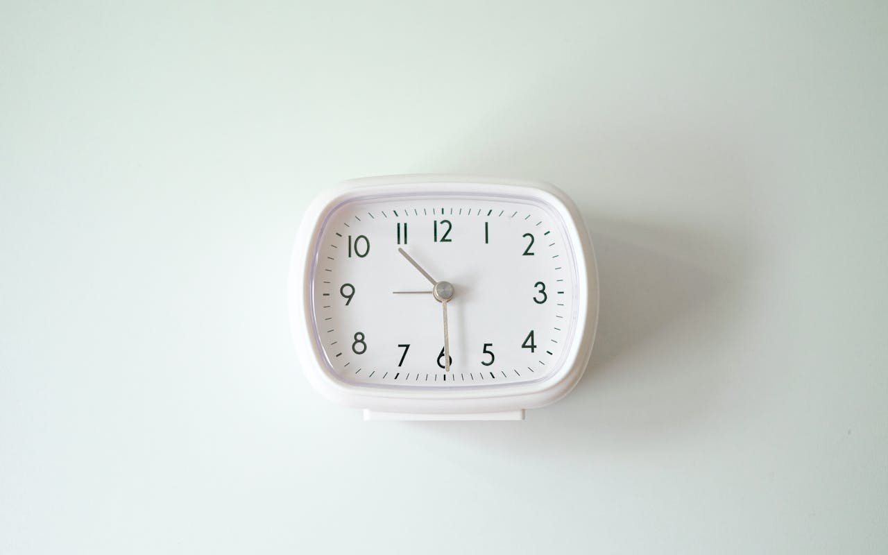 A simple white analog clock against a minimalist background signifying precision and time management.