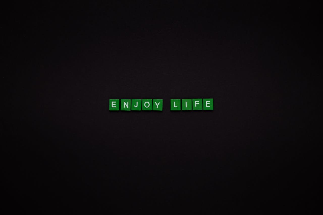 Green letter tiles spelling 'ENJOY LIFE' on a black background, perfect for motivational content.