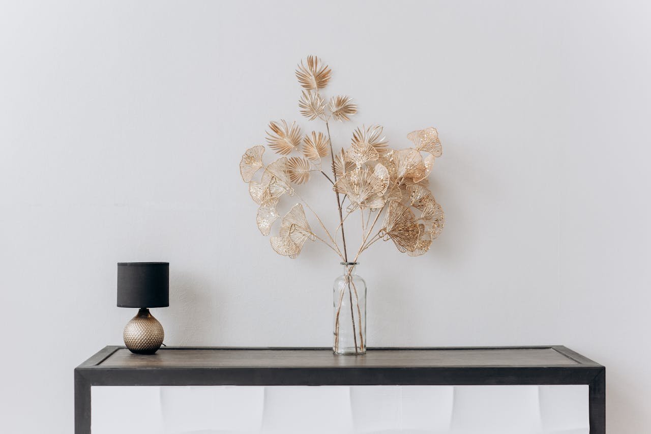 A stylish minimalist interior with a floral arrangement and a sleek lamp on a wooden table.